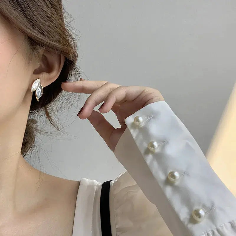 Close-up of a person wearing a silver earring with a plain background