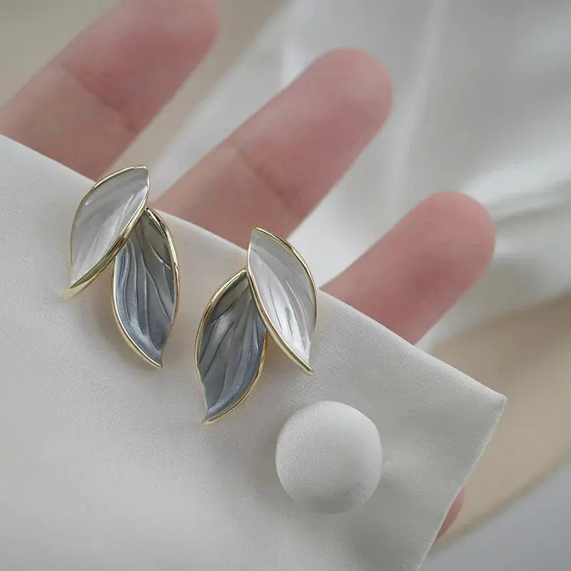 Leaf-shaped earrings with gold accents on a white surface
